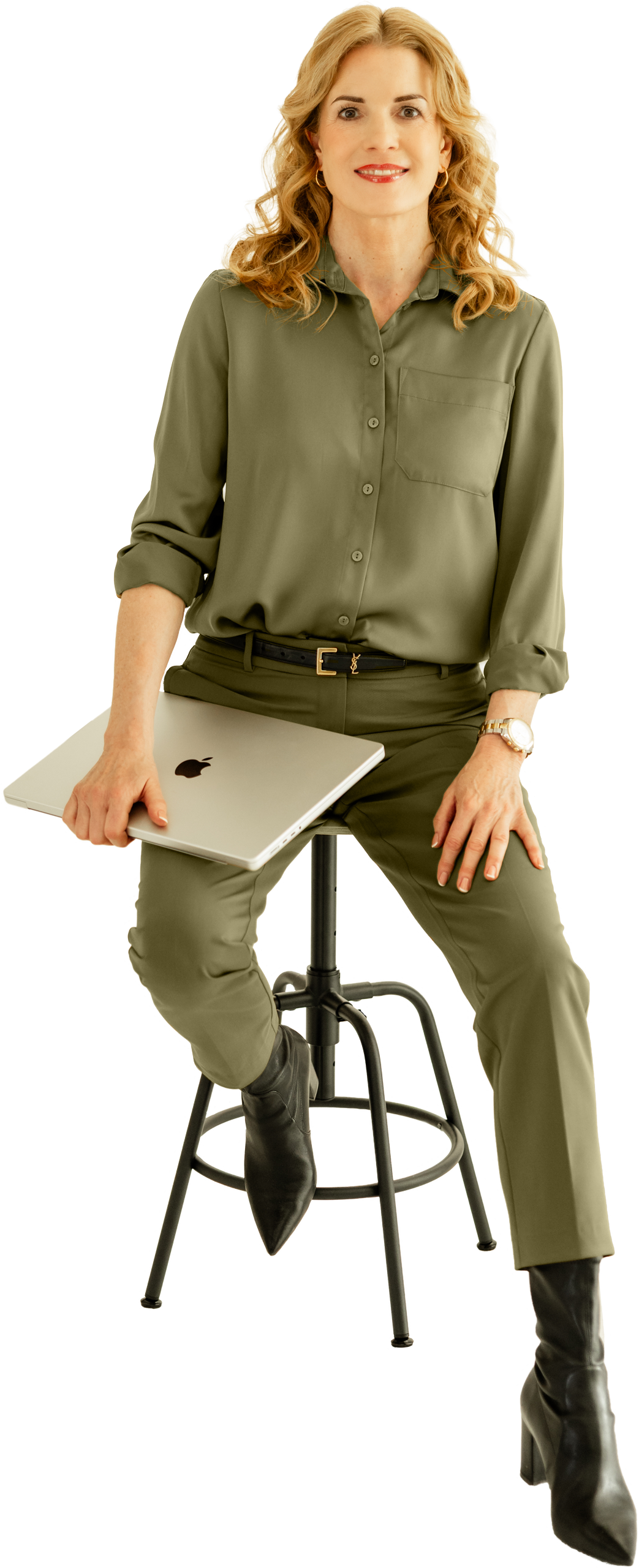 Ulrike Hostehradsky - Medienmanufaktur im KREATIVSTUDIO München Ulrike Hostehradsky sitzt auf einem Hocker und hält ein MacBook Pro in der Hand in der Medienmanufaktur im KREATIVSTUDIO München