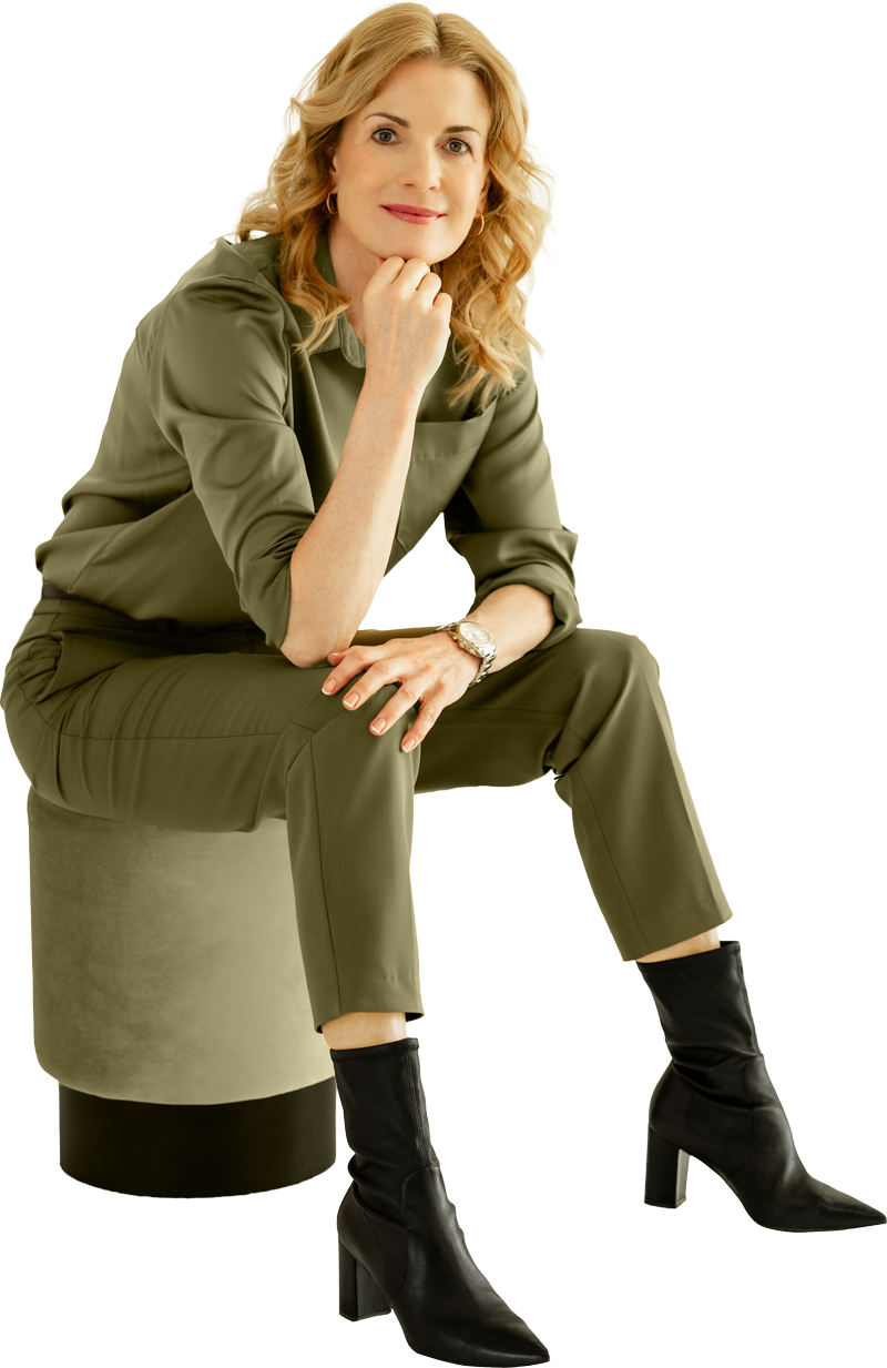 Ulrike Hostehradsky sitzt auf einem Hocker und stützt sich entspannt im KREATIVSTUDIO München